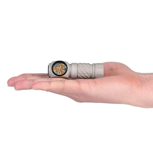 The Acebeam H17 2.0 headlamp, featuring three warm white LED bulbs, fits comfortably on an open palm to highlight its compact size.