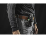 Person wearing jeans and a dark long-sleeve shirt, with a brown belt holding a black pouch containing the Armytek Predator Pro Max tactical flashlight attached to their right hip.