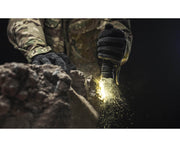 Wearing camo and gloves, a person uses the Armytek Predator Pro Max flashlight on rocky ground, making sparks fly.