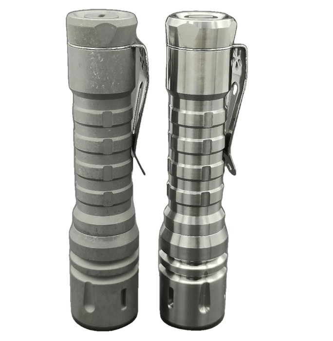 A pair of ReyLight LANapple - Ti flashlights on a black surface.