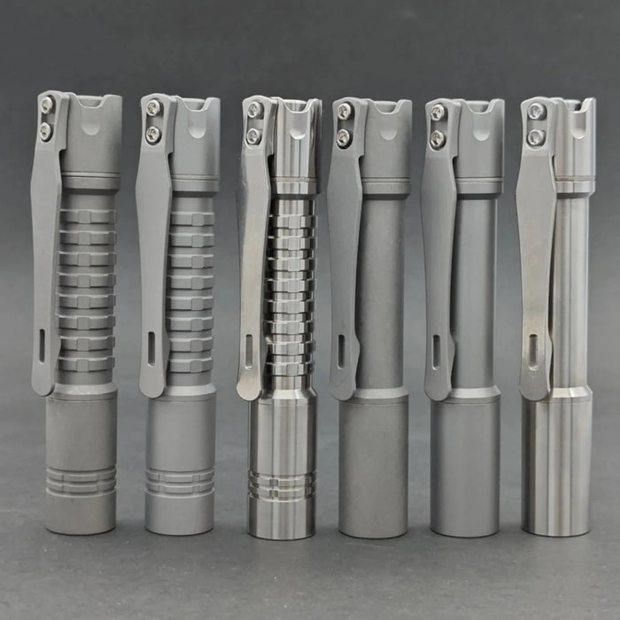 Six metal pens with clip attachments are lined up vertically against a plain background. Each pen, equipped like the ReyLight Pineapple Mini Ti - MK II, showcases a different textured grip design.