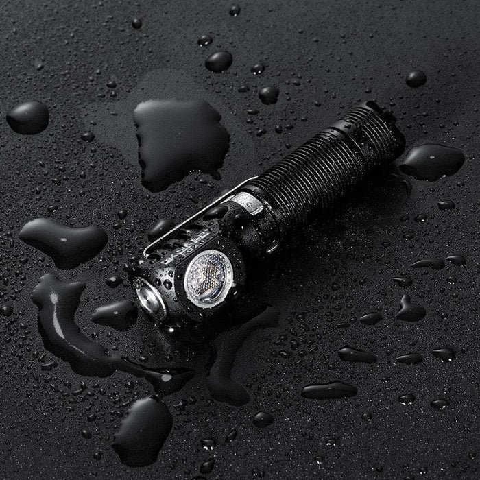 A Manker E02 II on a black surface with water on it.
