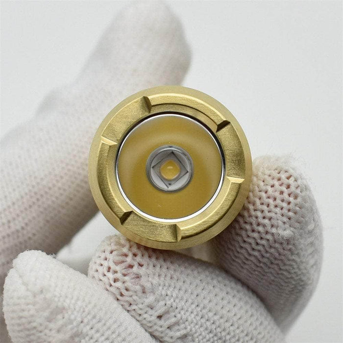 A person holding a ReyLight LAN Brass button with a white glove on it.