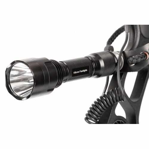 A black tactical flashlight is mounted on a piece of equipment with a coiled cable attached.