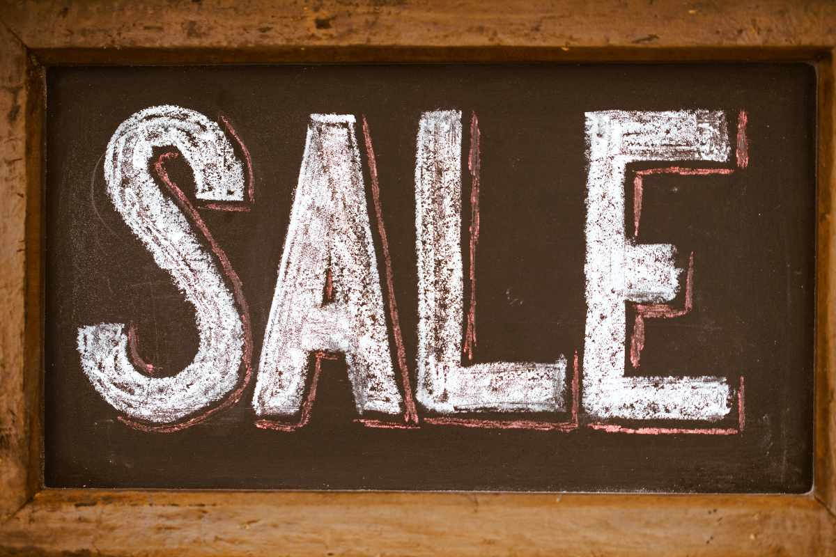 A chalkboard with the word "SALE" written in large, white chalk letters.