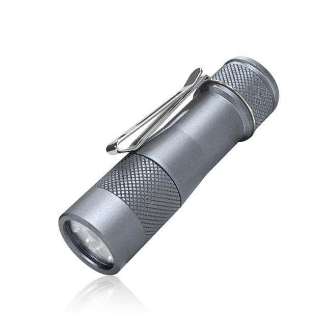 A compact, metallic gray flashlight with a textured grip and a metal pocket clip, shown against a white background.
