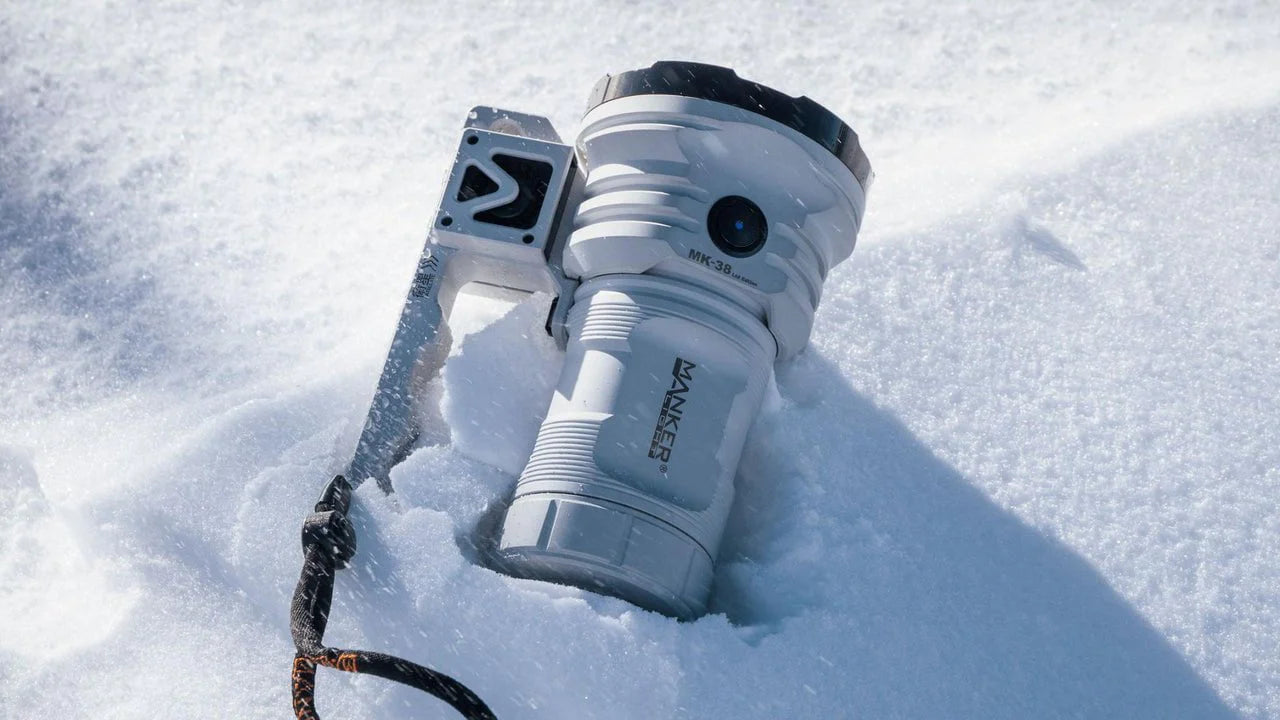 A large white flashlight with a wrist strap is partially buried in snow.