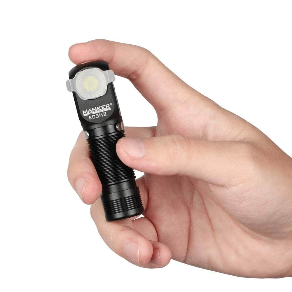 A hand holding a black Maiker E03H II compact flashlight, with the front LED facing upward.