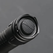 Close-up of the textured push button on the end of a black Acebeam T29 Ultra Long Range Hunting Flashlight against a gray background.