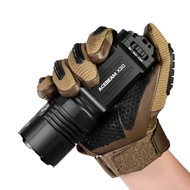 A gloved hand holds an Acebeam X30, a 20,000-lumen dual-source searching flashlight, against a white background.