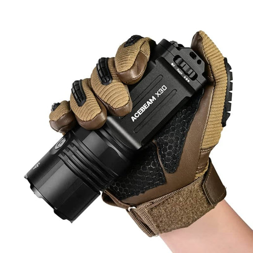 A gloved hand holds an Acebeam X30, a 20,000-lumen dual-source searching flashlight, against a white background.