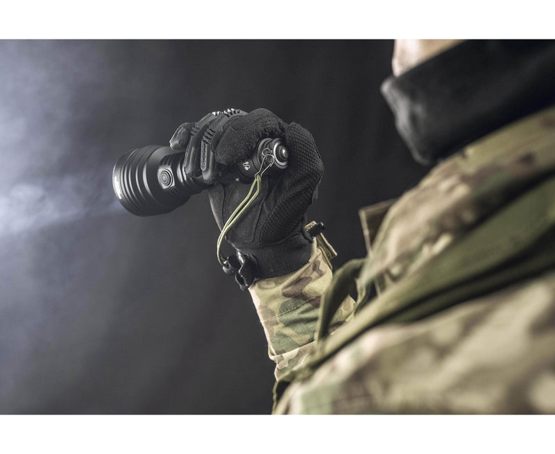 A person in camouflage clothing and gloves holds an Armytek Barracuda Pro Max Magnet USB flashlight and a night vision monocular against a dark background.