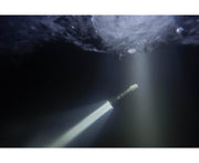 An Armytek Barracuda Pro Max Magnet USB flashlight beams upward through dark water, illuminating the icy surface above.