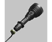 The Armytek Barracuda Pro Max Magnet USB is a black handheld flashlight with a ridged head and a cable attached for magnet USB charging, displayed against a plain gray background.