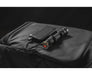 An Armytek Dobermann Pro Max is charging via USB from a power bank, both placed on a black textured bag.