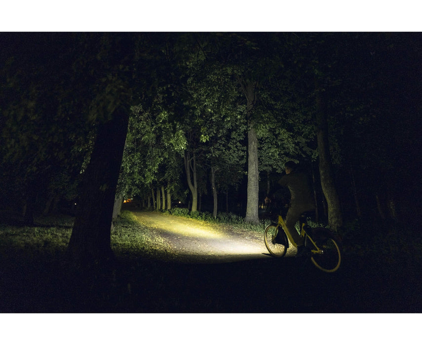 A person riding a bicycle with an Armytek Prime C1 Pro Magnet USB through the woods at night.