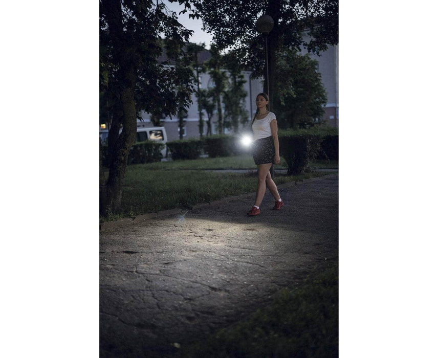 A woman walking down a path at night with an Armytek Prime C1 Pro Magnet USB flashlight.
