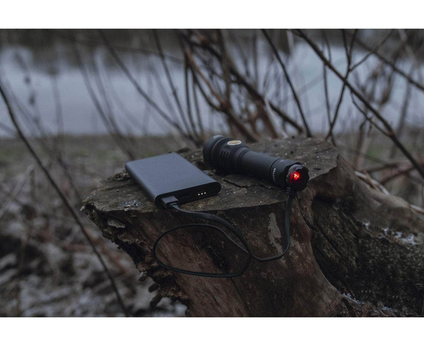 An Armytek Prime C2 Pro Max Magnet USB sitting on top of a tree stump.