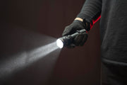 A gloved hand holds the Armytek Viking Pro Max Magnet USB - White flashlight, projecting a bright beam forward in the dark and showcasing its Magnet USB feature.