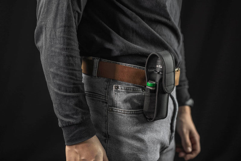 Person wears a black shirt, gray jeans, and brown belt, carrying a black pouch with an Armytek Viking Pro Max Magnet USB - White flashlight and battery on their right hip.