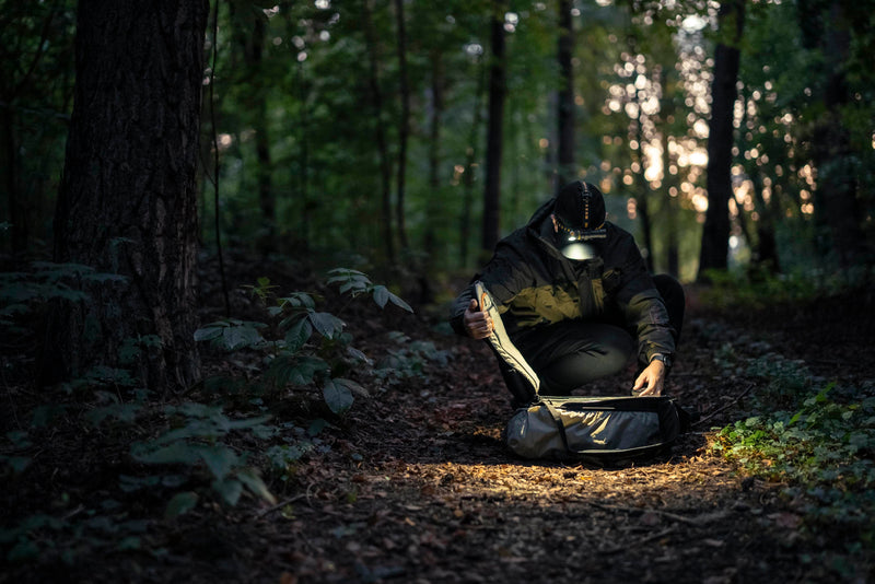 Elf C2 Max worn as a headlamp beside a gear bag in the forest