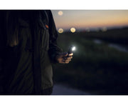 An Armytek Wizard C2 Pro Max LR - Warm woman holding a cell phone at night.