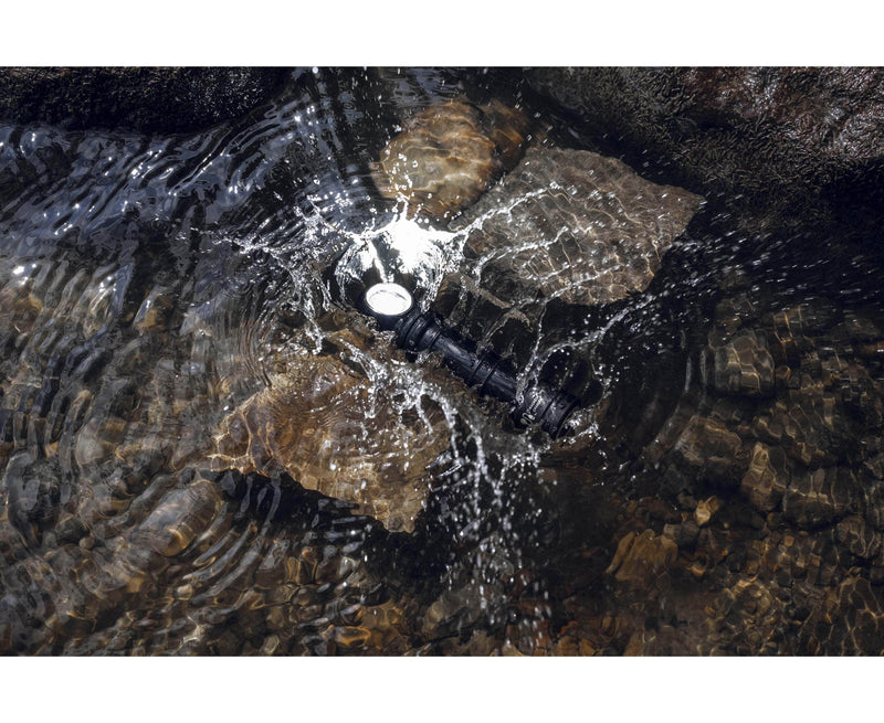 An Armytek Wizard C2 Pro Max LR - Warm flashlight in the water with a rock in it.