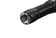 Close-up of the end cap and power button on the sleek black Fenix TK20R V2.0 tactical flashlight, emitting 3000 lumens, set against a shadowy backdrop.