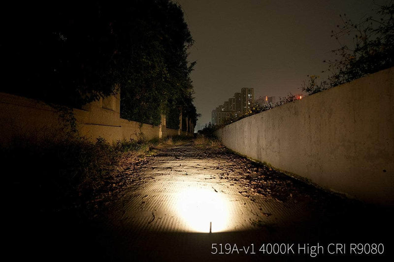 The Manker E02 III - Titanium lights up a leaf-strewn path at night with buildings beyond. Ideal for Everyday Carry, it delivers 560 lumens. Text reads: “519A-v1 4000K High CRI R9080.”.