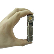 A hand holds the Manker E03H III - Titanium, a compact everyday carry flashlight with a textured grip, against a plain white background.