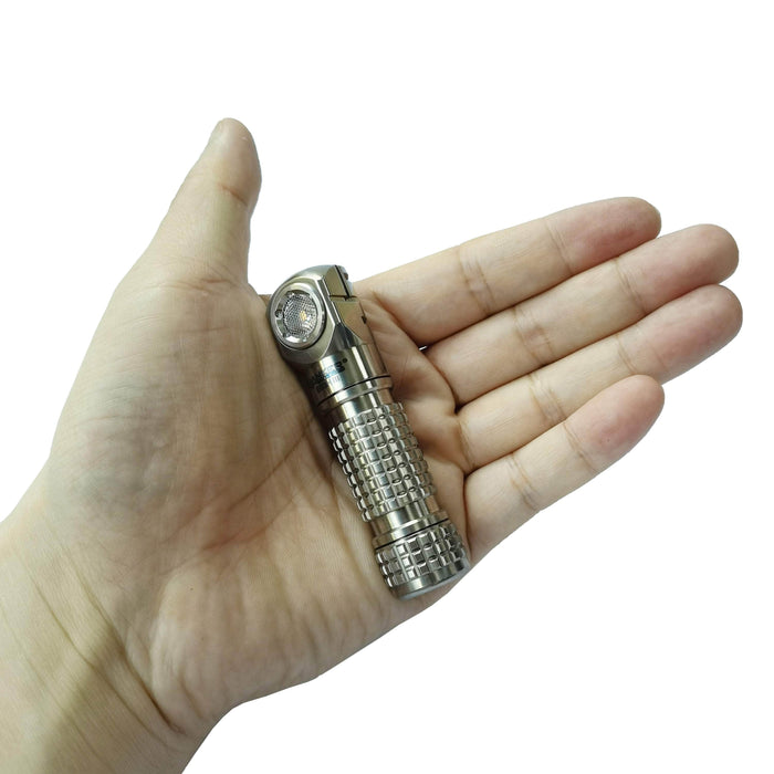 A hand holds the Manker E03H III - Titanium, a compact everyday carry flashlight with a textured grip and angled head, against a white background.