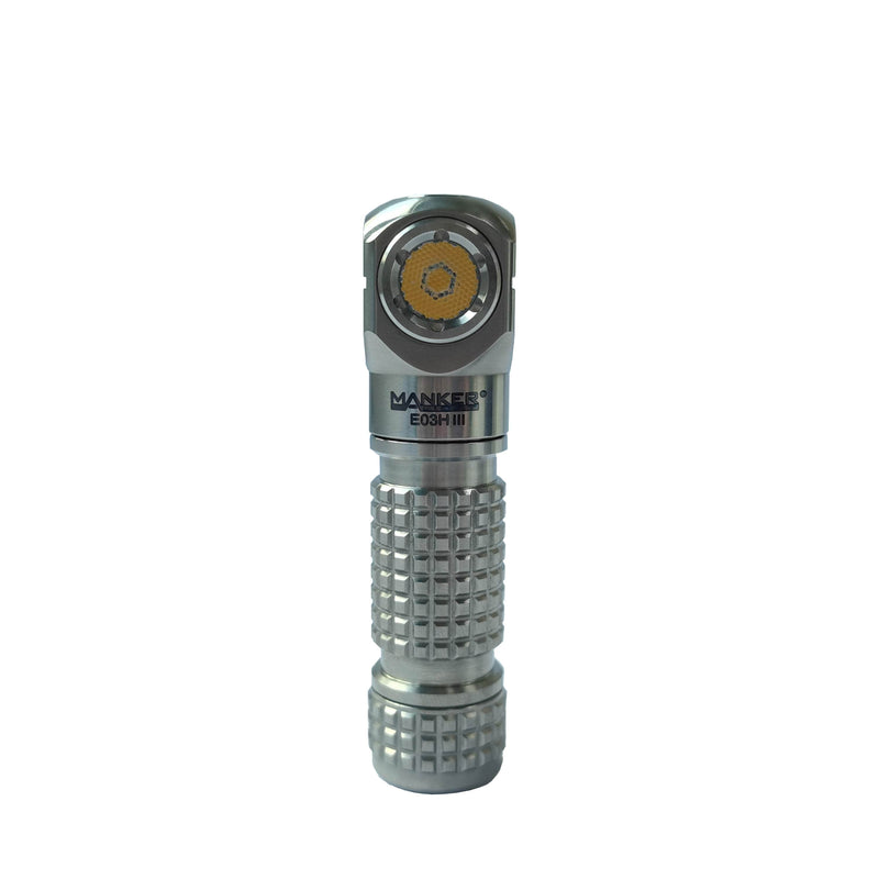 A compact, titanium Manker E03H III 1200 lumens flashlight stands upright against a plain white background, perfect as a powerful everyday carry or headlamp flashlight.