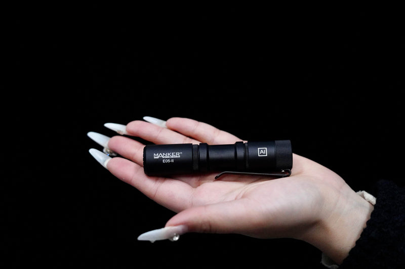 A person holding a Manker E05 II on a black background.