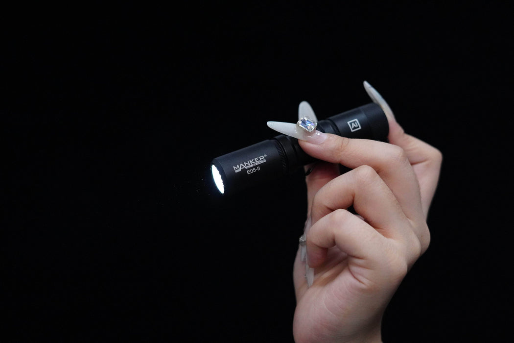 A person holding a Manker E05 II flashlight on a black background.