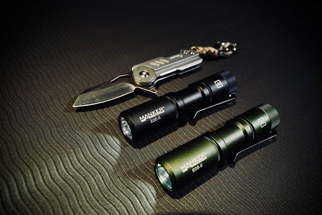 Two Manker E05 II flashlights and a knife on a table.