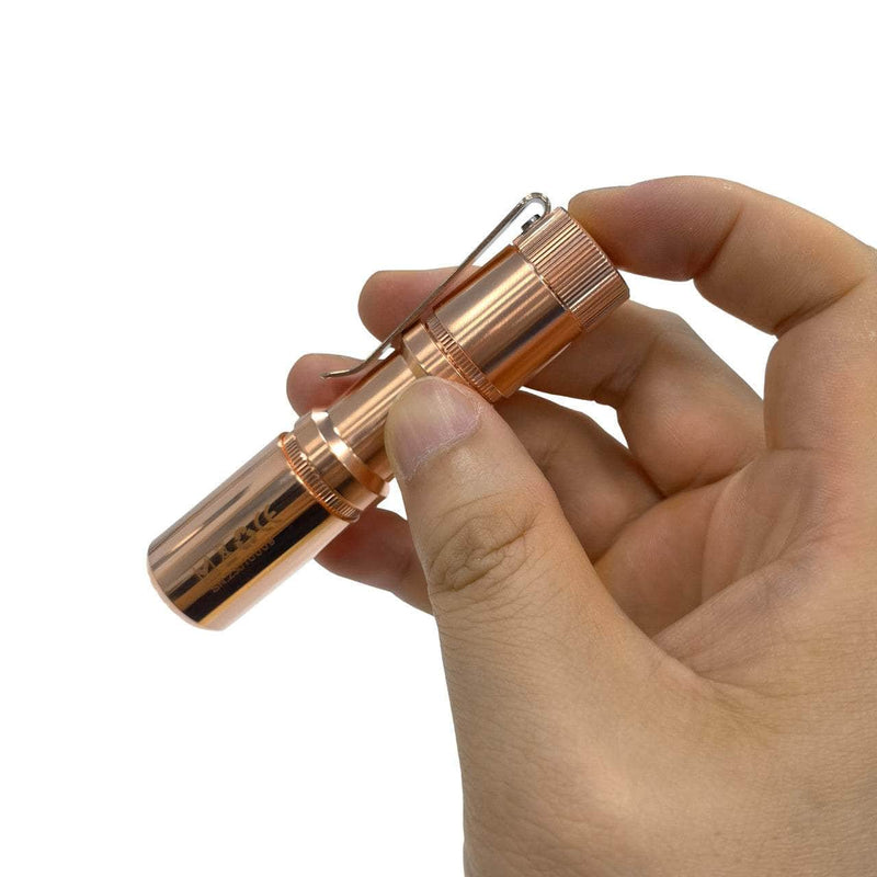 A person holding a compact Manker E05 II - Copper flashlight.