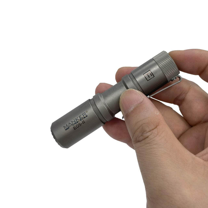 A person holding a Manker E05 II Ti flashlight.