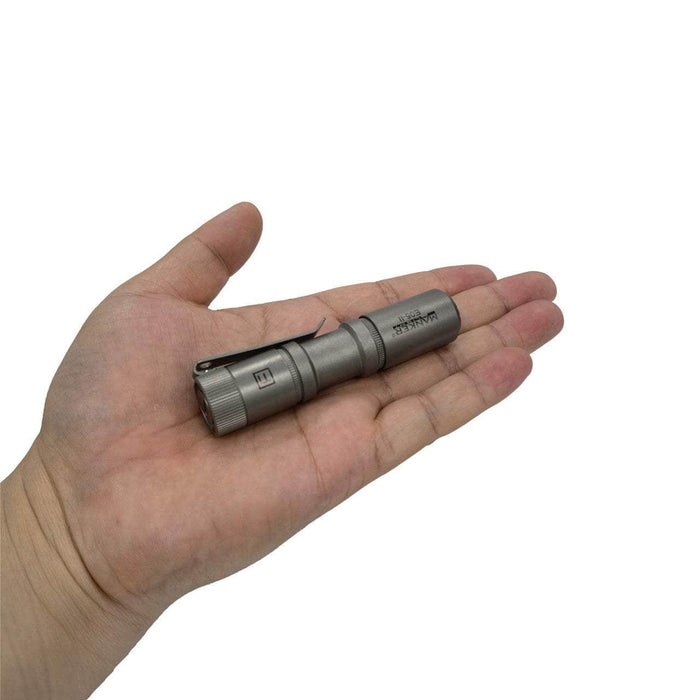 A person holding a Manker E05 II Ti flashlight in their hand.