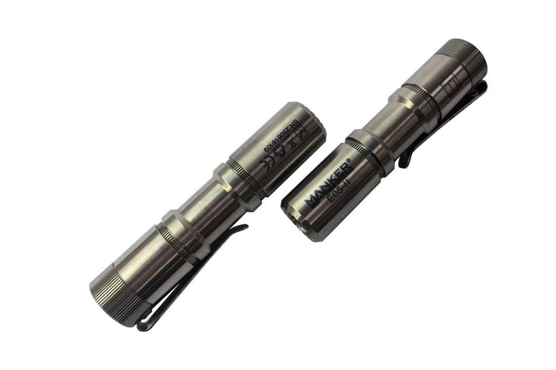 Two metallic Manker E05 II - TI Raw flashlights with pocket clips are side by side on a white background, showcasing these compact titanium units that deliver 1300 lumens—ideal for everyday carry.