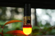 A Manker E14 IV flashlight with a red light attached to a plant.