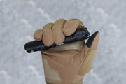 A gloved hand firmly holds the Manker MC11 III USB-C Rechargeable Tactical Flashlight against a blurred grey background.