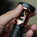 A person holding up a Manker MC13 II - SBT90.2 Copper/Black Limited Edition flashlight with a usb port.