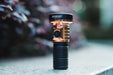 A Manker MC13 II - SBT90.2 Copper/Black Limited Edition flashlight sitting on the ground.