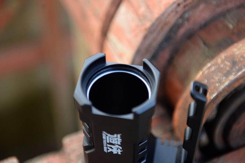 Close-up of the Manker Ranger MK39 II, a black metallic flashlight with a notched bezel, resting on rusted metal, designed for long-range illumination.