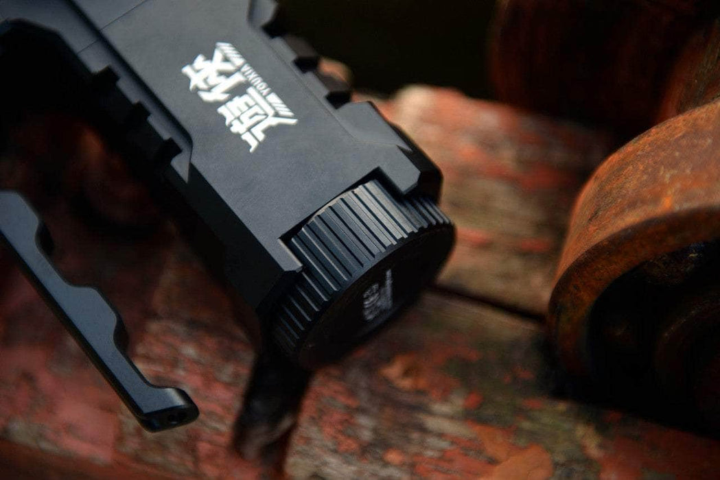 The Manker Ranger MK39 II, a black mechanical device with a textured knob, sits prominently on the rusty, weathered wooden surface like a spotlight.