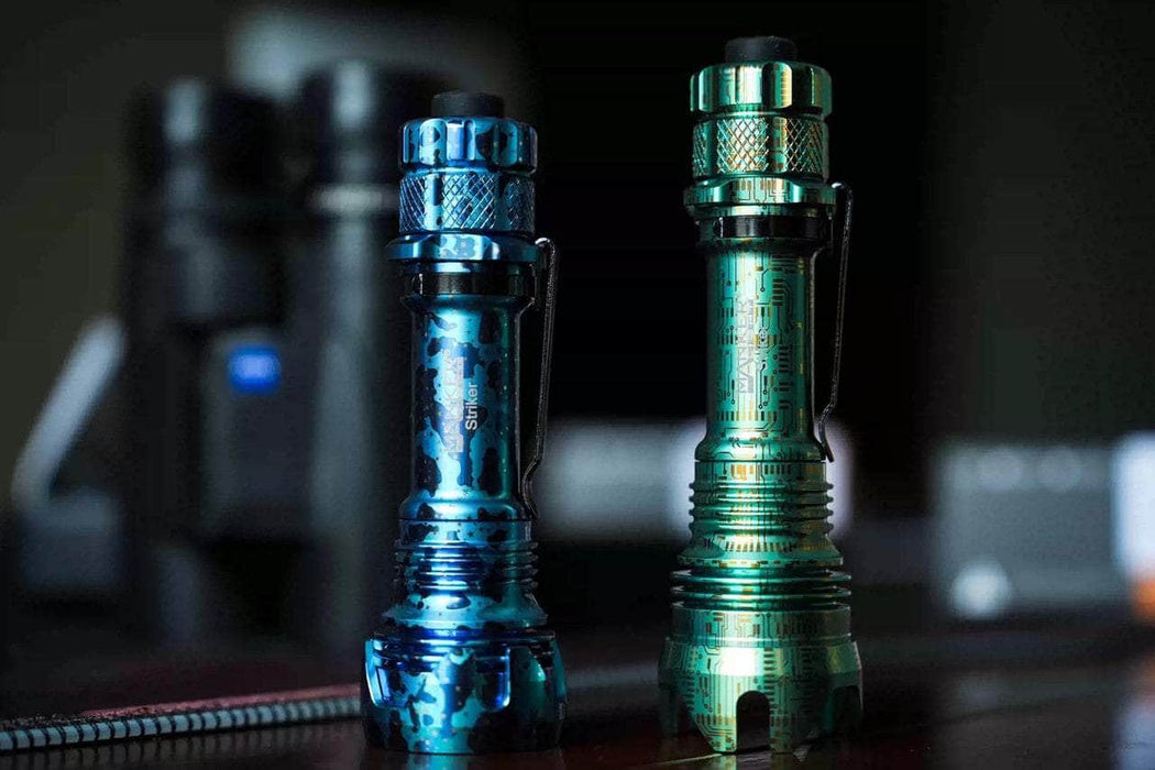 Two Manker Striker Limited Edition flashlights on a table next to each other.