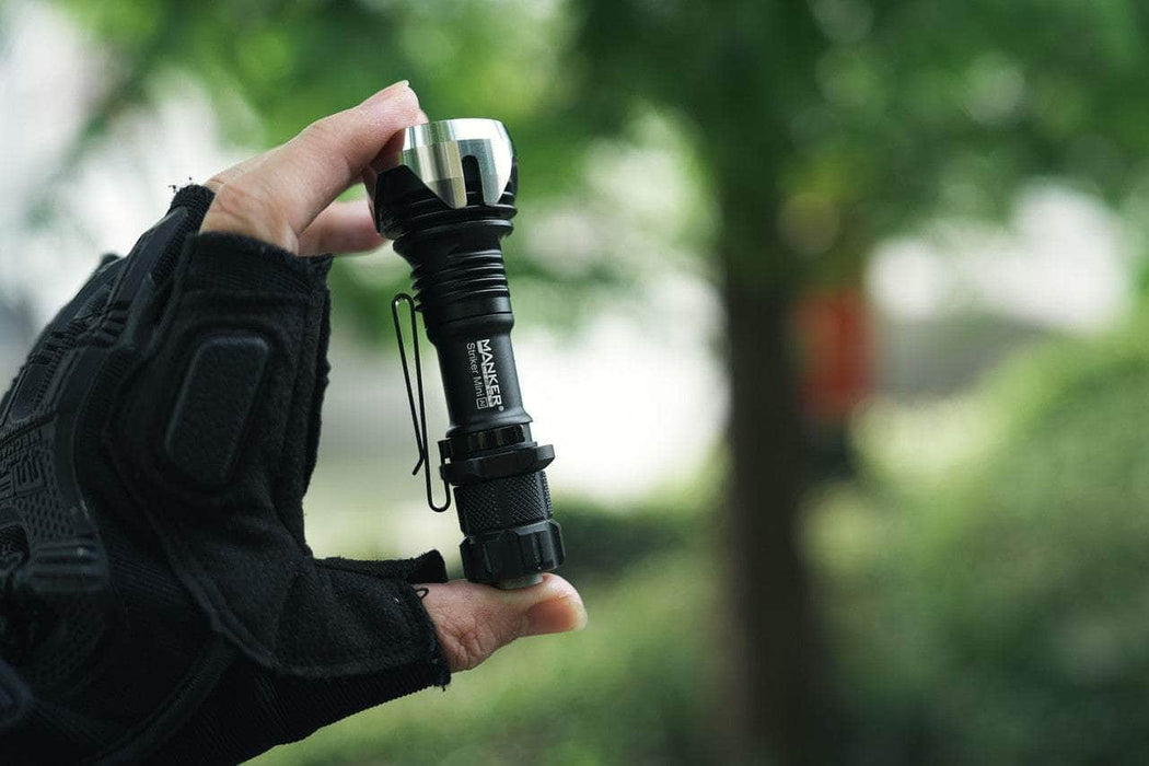 A person holding a Manker Striker Mini flashlight in their hand.