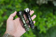 Two Manker Striker Mini flashlights in a person's hand.