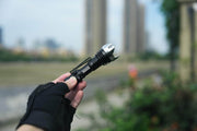 A person holding a Manker Striker Mini in front of a city.
