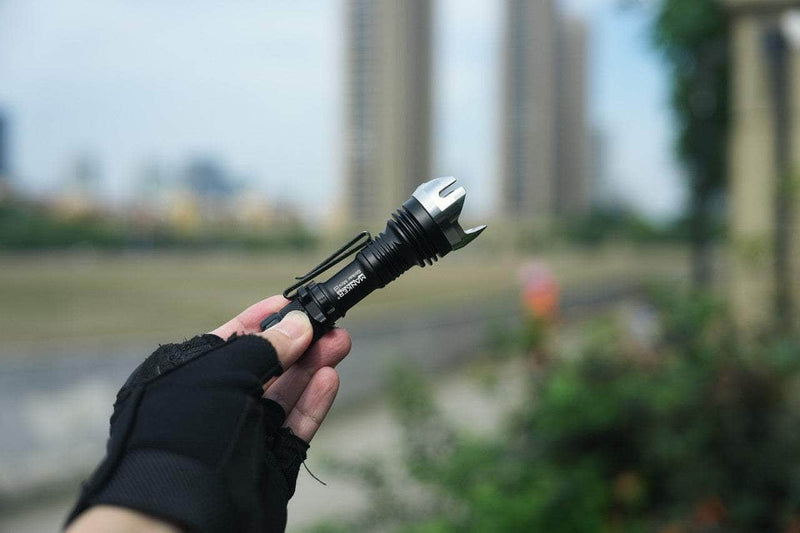 A person holding a Manker Striker Mini in front of a city.